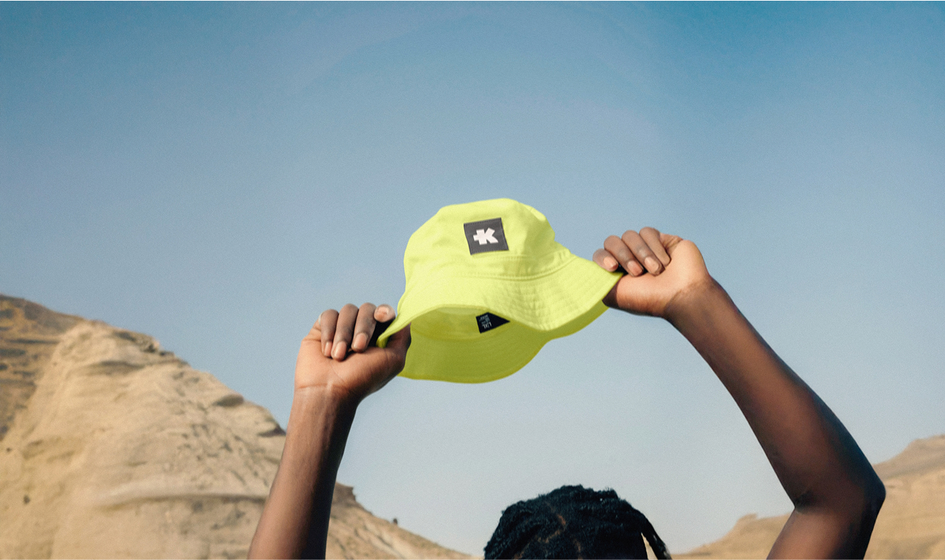 Person holding yellow cap in desert landscape